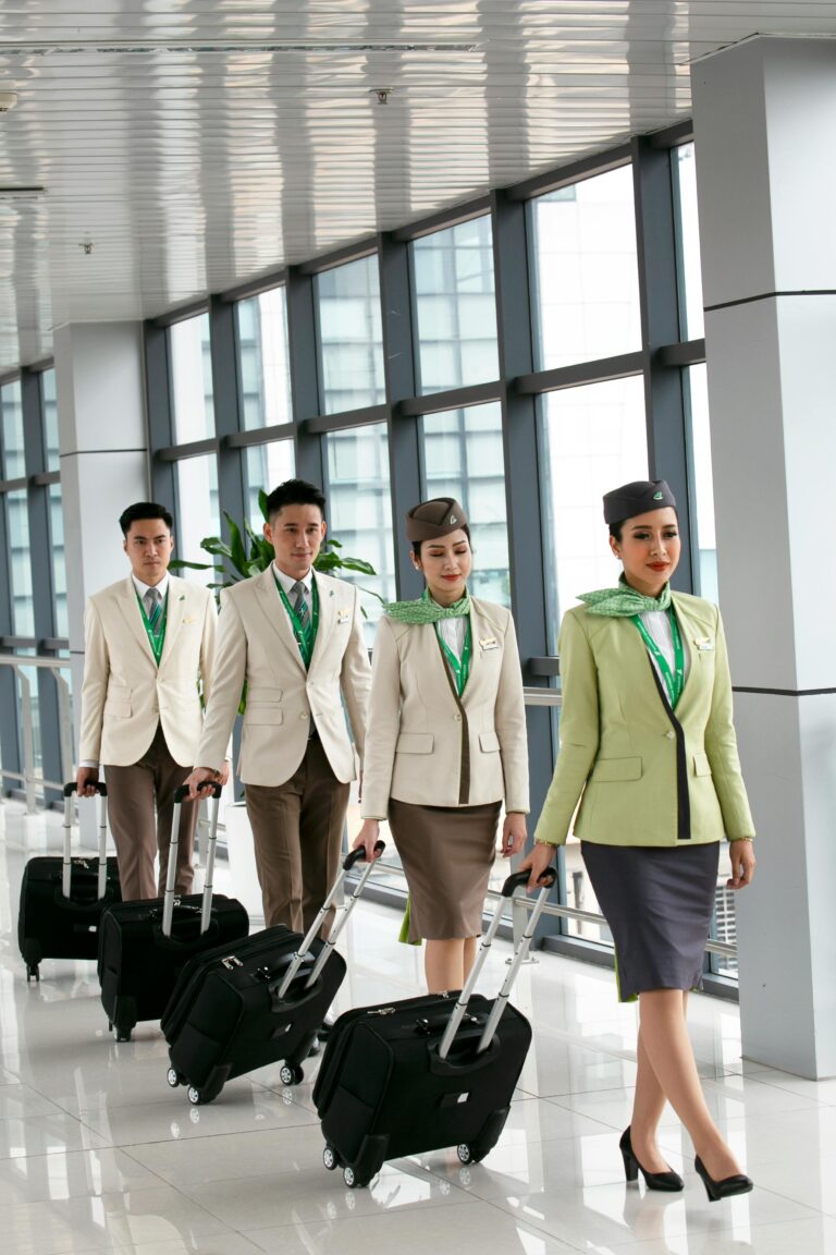 Airline crew in matching uniforms walking through a modern airport terminal with luggage.